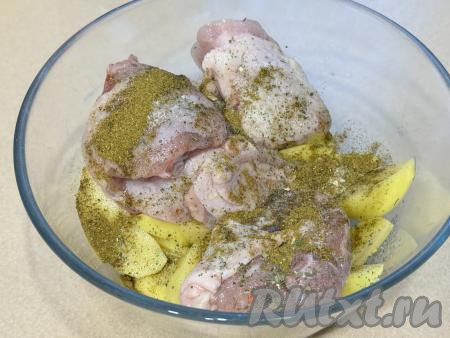 В глубокую миску выложить&nbsp;куриные бёдра, добавить дольки картошки, влить растительное масло, всыпать соль и специи (в качестве специй я использовала 1 чайную ложку хмели-сунели и соль со специями).&nbsp;