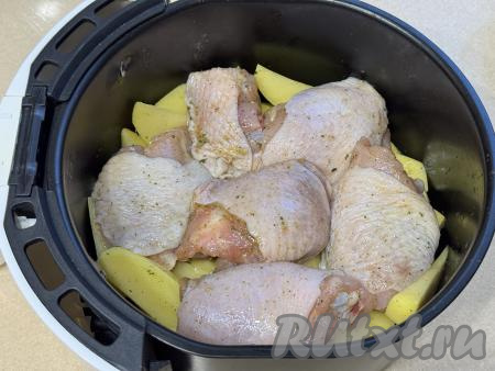 В чашу аэрогриля на решётку выложить ровным слоем дольки картошки. Поверх картофеля в один слой разложить куриные бёдра. Отправить чашу в аэрогриль.&nbsp;Выставить температуру аэрогриля 200 градусов на 10 минут. Затем достать чашу, немного встряхнуть, чтобы картофель перемешался. Снова отправить чашу в аэрогриль, сразу убавить температуру до 180 градусов и запекать картошку с куриными бёдрами ещё 40 минут (до готовности картофеля и мяса). Каждые 10 минут чашу нужно доставать из аэрогриля и встряхивать, чтобы картофель немного переворачивался, благодаря этому картошка будет равномерно пропекаться и не будет подгорать. Бёдрышки можно тоже периодически переворачивать.