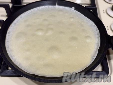 Сковороду (я взяла сковородку диаметром 20 сантиметров) хорошо разогреть, уменьшить огонь до среднего, перед жаркой первого блина немного смазать растительным маслом. Уменьшить огонь до среднего, влить в сковороду небольшой половник теста. Сразу равномерно распределить тесто по дну сковородки.&nbsp;