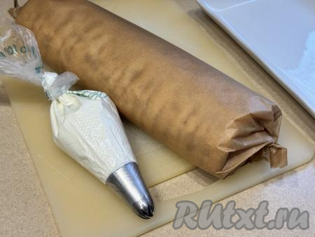 Завернуть рулет в лист пергамента и поместить в холодильник на 2-3 часа для пропитки. Кулинарный мешок с кремом тоже убрать в холодильник.