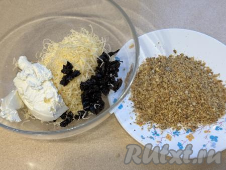 В миску с натёртым сыром добавить творожный сыр. Сюда же выложить мелко нарезанный чернослив, по желанию, всыпать соль.&nbsp;