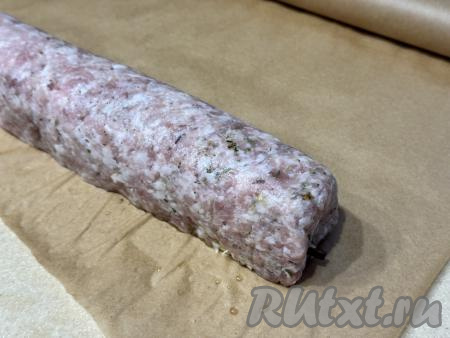 Подготовленный рулет из фарша с начинкой из грибов и сыра переложить на лист пергамента.