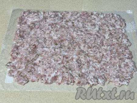На обычный целлофановый пакет, расстеленный на столе, выложить фарш и равномерно распределить его ровным слоем. Получится прямоугольник из фарша.