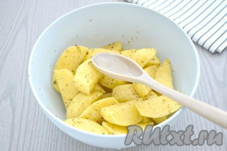 К долькам картошки, покрытым специями, вливаем растительное масло. Снова хорошо перемешиваем, покрывая картофель маслом со всех сторон.