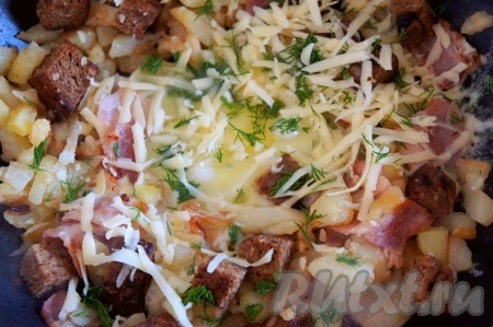 Добавить тёртый сыр, мелко нарезанную зелень, убавить огонь и снова накрыть сковороду крышкой. Готовить ещё 1 минуту, пока не расплавится сыр.