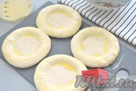 Дном обычного стакана (диаметр дна стакана у меня был 6 сантиметров) в центре заготовок делаем углубление. Бортики заготовок ватрушек смазываем оставшейся яичной смесью.