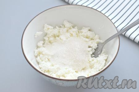 Прежде всего достаём пласт слоёного теста из морозилки и оставляем размораживаться при комнатной температуре (размороженное тесто должно стать достаточно мягким). Для формирования ватрушек можно купить как дрожжевое (его я и использовала), так и бездрожжевое слоёное тесто. Когда тесто разморозится, сразу приступаем к приготовлению творожной начинки для ватрушек. Для этого творог любой жирности выкладываем в миску, всыпаем сахар, растираем вилкой до однородности.