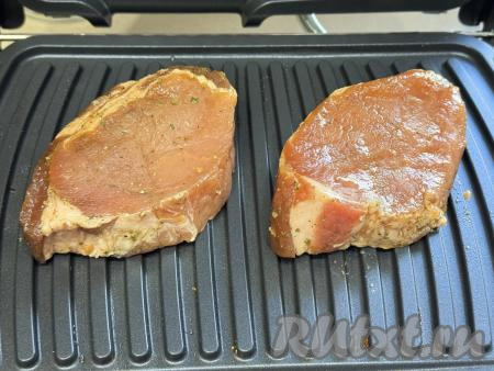 Разогреть электрогриль, выставить режим "Мясо", выложить стейки из свинины на панель гриля.