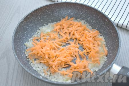 К луку, обжаренному до прозрачности, выкладываем натёртую на крупной тёрке морковь, сразу перемешиваем. Обжариваем овощи минут 5-6 (до мягкости моркови), время от времени помешивая.