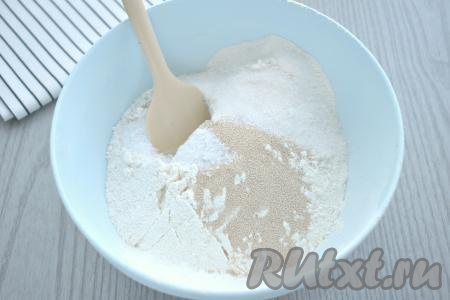 В глубокую миску просеиваем пшеничную муку, всыпаем дрожжи, сахар и соль, перемешиваем сухие ингредиенты, образуя в центре воронку.