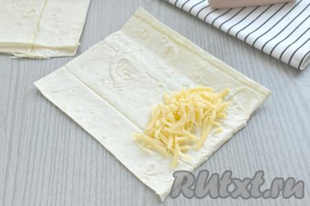 С одной более узкой стороны прямоугольника из лаваша, отступая от краёв, как минимум, по 1 сантиметру выкладываем 1/4 часть натёртого сыра.