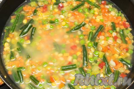 В сковороду с булгуром и мексиканской смесью влить 400 миллилитров кипящей воды, посолить, перемешать, дать воде закипеть, уменьшить огонь до минимума.