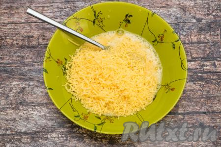 Сыр натереть на мелкой тёрке и добавить в тарелку с яичной смесью.