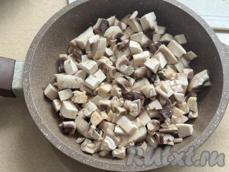 В сковороду влить растительное масло, разогреть. Шампиньоны (или предварительно отваренные лесные грибы) нарезать на средние кусочки и выложить в разогретую сковороду.&nbsp;