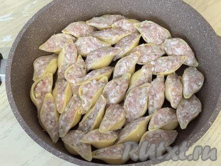 Остывшие ракушки наполнить фаршем и выложить их в объёмную сковороду в один слой. У меня сковорода диаметром 28 сантиметров.