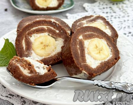 Аппетитные кусочки рулета, приготовленного из печенья и банана без выпечки, выложить на тарелку и подать вкусный, нежный десерт к столу.