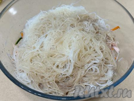 В миску с овощами добавить нарезанное копчёное мясо курицы и подготовленную фунчозу, сразу влить в получившийся салат соевый соус, растительное масло и уксус.