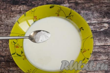 Кефир влить в глубокую тарелку, добавить соду, очень хорошо перемешать. Оставить на 5-7 минут, за это время сода вступит в реакцию с кефиром, поэтому смесь слегка увеличится в объёме, на её поверхности появятся пузырьки.