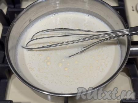 Как только молоко начнёт закипать, начать тонкой струйкой вливать желтковую смесь, непрерывно и интенсивно перемешивая венчиком.&nbsp;