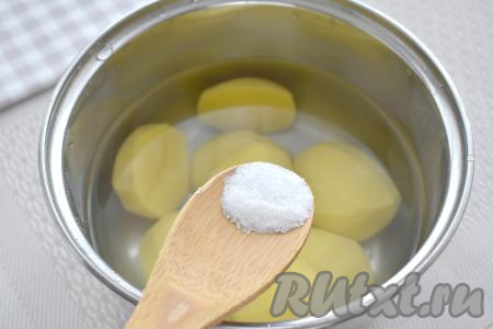 Картошку очищаем. Если картофель крупный, разрезаем его на несколько частей, выкладываем в кастрюлю, сразу заливаем полностью водой, по вкусу солим и ставим на сильный огонь. После закипания, уменьшив огонь, варим картошку до готовности (минут 25, готовый картофель должен легко прокалываться вилкой).