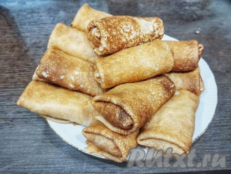 Готовые блины, фаршированные капустой и грибами, выкладываем на тарелку. Всего на сковороде диаметром 24 сантиметра я испекла 23 блинчика, а начинки хватило ровно на 20 блинов.