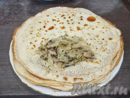 Затем готовый тонкий блинчик перекладываем со сковороды на тарелку, по желанию, смазываем сливочным маслом. Перемешивая тесто перед жаркой очередного блина и смазывая сковороду маслом только по мере необходимости, постепенно готовим все блинчики, складывая их стопочкой на тарелку и, по желанию, смазывая сливочным маслом. Как только все блины будут пожарены, можно начинать их фаршировать. Для этого, отступая от краёв блина, выкладываем 1 столовую ложку с верхом начинки из капусты и грибов.