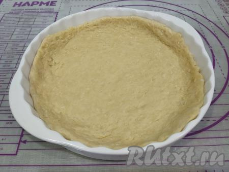 Одну часть теста на присыпанной мукой поверхности раскатываем скалкой в круг, диаметр которого должен быть немного больше размера формы для выпечки. Тесто мягкое, поэтому раскатывается оно хорошо. Пирог я выпекала в форме диаметром 26 сантиметров. Форму для выпечки смазываем растительным маслом, выкладываем раскатанное тесто, формируем из теста бортики.