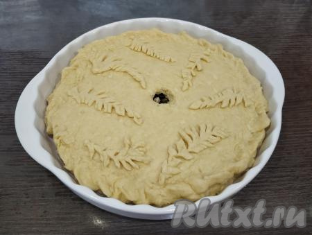 Вторую часть теста раскатываем в круг такого же диаметра, как была раскатана первая часть теста, накрываем начинку, скрепляя края с первой частью теста. Из ранее отложенной части теста делаем украшение и выкладываем его на пирог. В середине пирога с помощью ножа аккуратно вырезаем отверстие для выхода пара. Оставляем пирог для расстойки минут на 20.