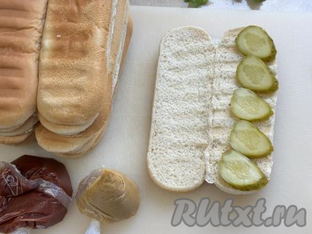 Теперь можно приступать к сборке хот-догов. Для этого булочку для хот-дога, обжаренную на электрогриле, нужно разрезать вдоль на две половинки. На нижнюю половинку выложить в один слой кружочки огурца.