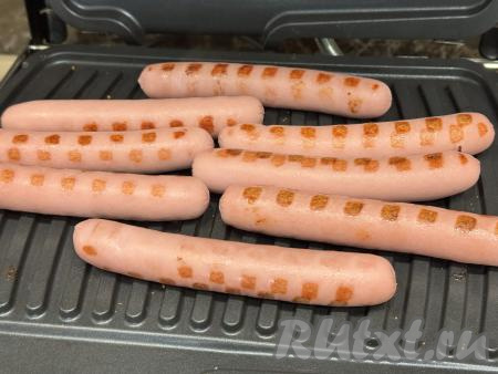 Затем булочки убрать и выложить на электрогриль сосиски в один слой, закрыть створки электрогриля. Жарить сосиски на режиме&nbsp;№ 2 "Сосиски, котлеты" в течение 4 минут (до подрумянивания сосисок).