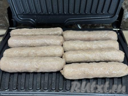 Достать купаты из кастрюли. Переложить купаты на разогретый электрогриль в один слой. Панели гриля маслом можно не смазывать.