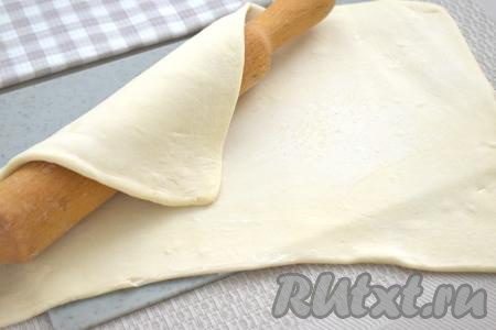 На поверхность, присыпанную мукой, выкладываем разморозившийся пласт слоёного теста, раскатываем его скалкой в одном направлении до толщины примерно 3 миллиметра