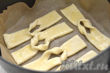 Чашу аэрогриля застилаем пергаментом. Столько полосок теста, сколько у вас одновременно поместятся в чашу аэрогриля, смазываем взбитым яйцом. Заготовки хвороста, смазанные яйцом, на небольшом расстоянии друг от друга выкладываем в застеленную чашу аэрогриля. У меня одновременно в чашу аэрогриля помещаются 5 полосок, поэтому весь хворост я выпекала в 4 этапа.