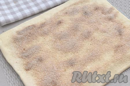 ​​​​​​​​​​​​Поверхность раскатанного теста равномерно посыпаем смесью сахара и корицы, отступая от краёв теста по 1 сантиметру.