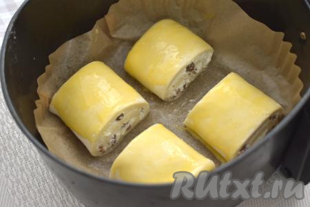 Яичный желток взбалтываем вилкой до однородности. С помощью силиконовой кисточки смазываем поверхность слоек взбитым желтком. Чашу аэрогриля застилаем пергаментом, выкладываем подготовленные слойки так, чтобы сторона, смазанная яйцом, была сверху. Отправляем чашу в аэрогриль.