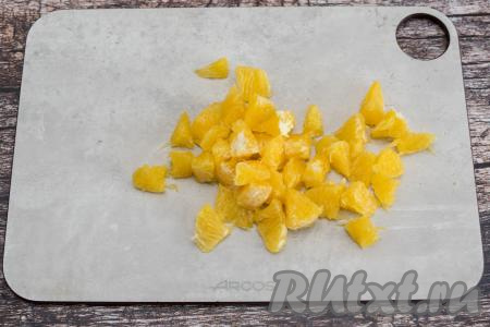 Очищенные дольки апельсина нарезать ножом на части, убирая косточки, если они есть.