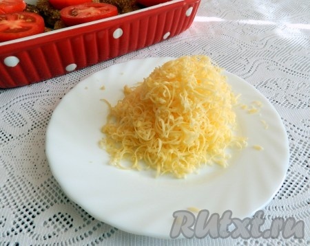 Сыр натереть на мелкой тёрке. Форму с котлетами вынуть из духовки, посыпать сыр сверху помидоров и снова поставить в духовку на 5 минут, чтобы расплавился сыр.