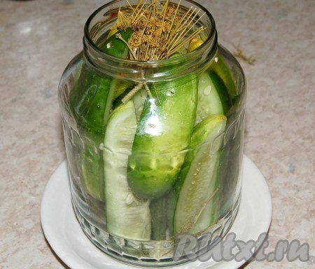 Взять чистую банку, плотно уложить в нее огурцы и специи.