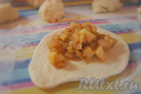 Стол присыпаем мукой. От приготовленного заранее теста отделяем небольшие кусочки - будущие пирожки. Каждый из них раскатываем, в центр выкладываем яблочную начинку.