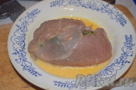 Свернуть куриное филе так, чтобы яйцо полностью оказалось внутри. Сырое яйцо разбить в тарелку, взбить его вилкой до однородности. Куриный рулет с варёным яйцом внутри аккуратно обмакнуть со всех сторон во взбитое яйцо.
