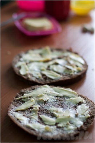 У ржаного хлеба срежьте верхнюю часть, а оставшуюся половинку хлеба разрежьте на два слоя. Желательно, чтобы оба коржа были не слишком толстыми. Вы же не хотите сделать неправильный бутерброд! Каждый корж смажьте сливочным маслом.