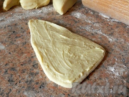 Из теста раскатать треугольники, смазать поверхность маслом.