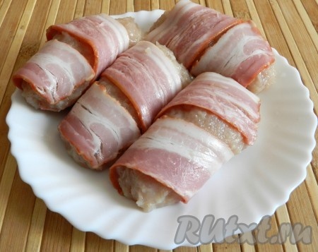 Добавить в куриный фарш яйцо, посолить (учитывая солёность бекона, в который в дальнейшем будут заворачиваться котлеты), поперчить и перемешать фарш до однородности. Из готового куриного фарша сформировать котлеты и каждую котлетку обернуть одной или двумя полосками бекона.
