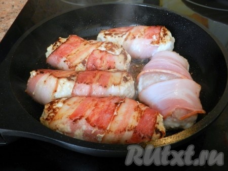 Обжаривать куриные котлеты в беконе на разогретой сковороде на растительном масле с двух сторон до румяной корочки на среднем огне. Затем уменьшить огонь, влить немного воды (примерно, 20 мл), накрыть крышкой и протушить до готовности (примерно, 10-15 минут).
