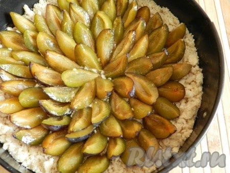 В форму для выпечки выложить 3/4 теста-крошки, сверху в произвольном порядке разложить сливы.