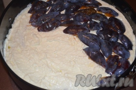 Достать форму с тестом из духовки, сверху распределить творожную начинку и слой порезанных на дольки слив.