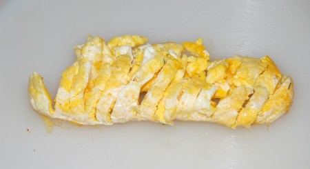 Затем омлет свернуть рулетиком и нарезать на тонкие кусочки.