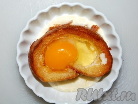 Для другой формочки белый хлеб нарезаем на куски, толщиной в два пальца, вынимаем мякиш, обжариваем на любом масле до легкой румяности. На дно формочки выливаем немного сметаны, на нее выкладываем кусок обрезанного хлеба, во внутрь хлеба выливаем яйцо, стараясь не повредить желток, солим.