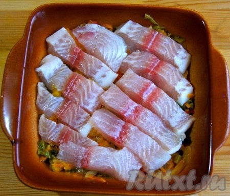 Филе рыбы помыла, обсушила, нарезала на средние кусочки, уложила на овощную подложку, посолила, поперчила.