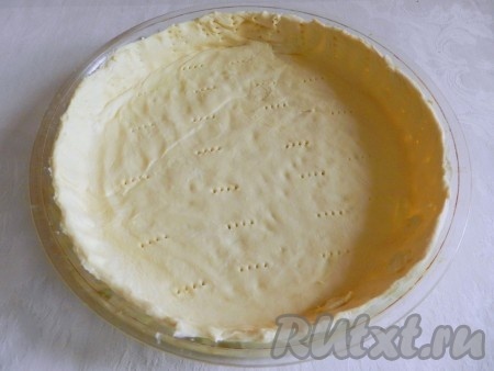 На присыпанной мукой поверхности раскатать тесто до толщины 4 миллиметра. Форму для выпечки смазать растительным маслом. Раскатанное тесто выложить в форму для выпечки, сделав бортики. Для того чтобы тесто сильно не вздувалось в процессе выпечки, наколоть основание будущего пирога вилкой. Поставить форму с тестом в разогретую до 200 градусов духовку на 10 минут.